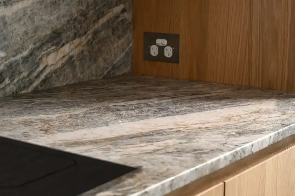Countertop with marble and wood paneling, an electrical outlet is visible.