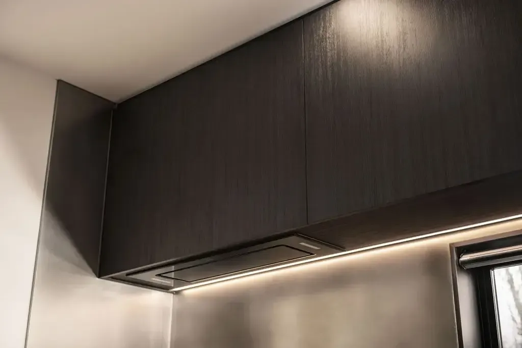 Dark wood kitchen cabinets with under-cabinet lighting and a range hood.