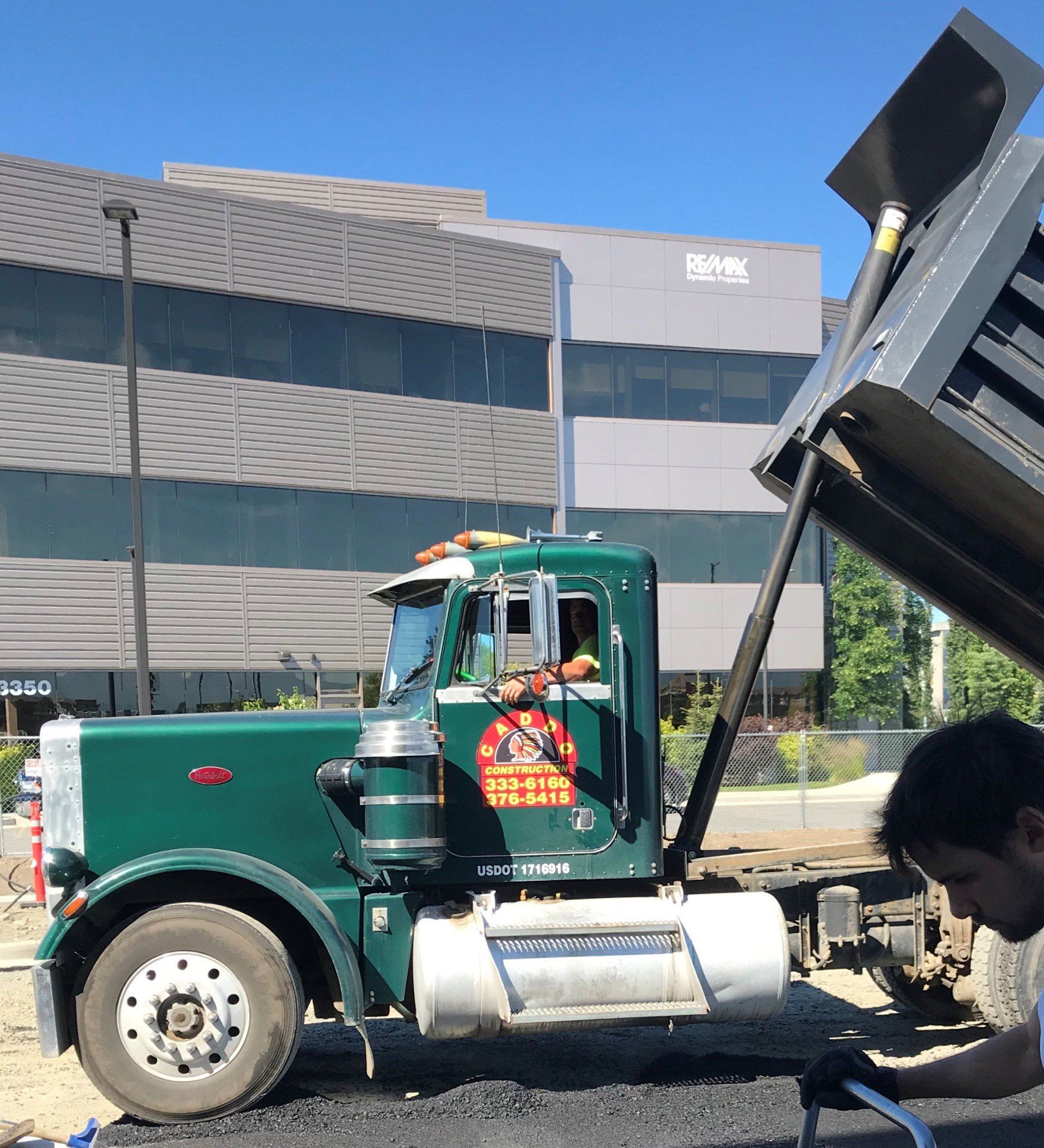 A man is working on a truck in front of a building.