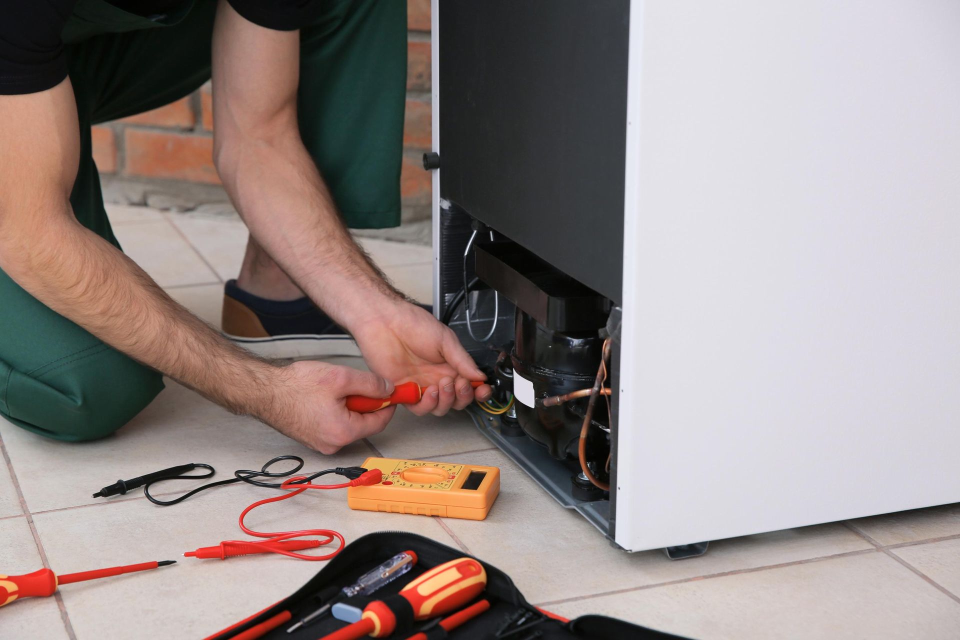 Technician using red screwdriver to repair the back of a computer case on the floor
