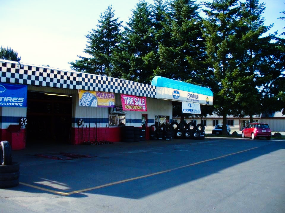 A row of tires are stacked in front of a tire shop. | TIRE NATION & AUTO REPAIR POINT S
