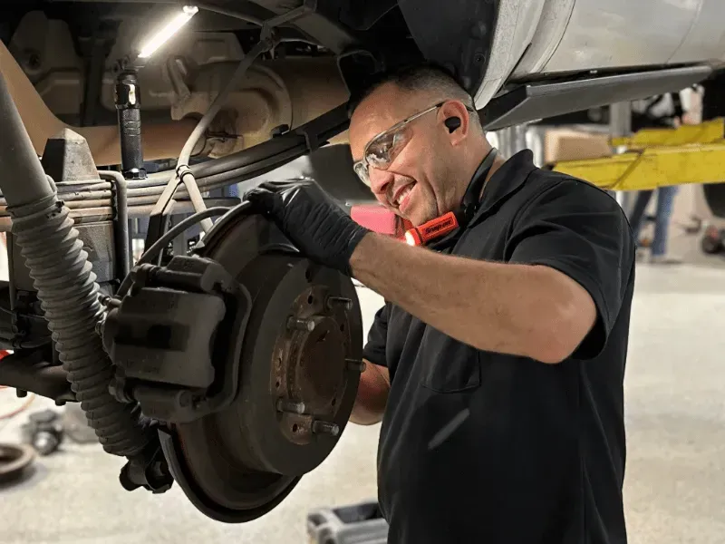 A man is working on a car in a garage. | TIRE NATION & AUTO REPAIR POINT S