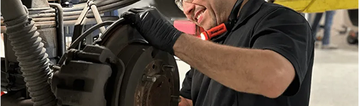 A man is working on a car in a garage. | TIRE NATION & AUTO REPAIR POINT S