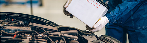 A mechanic is holding a battery while working on a car. | TIRE NATION & AUTO REPAIR POINT S