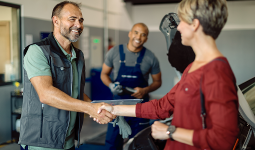A man and a woman are shaking hands in a garage. | TIRE NATION & AUTO REPAIR POINT S