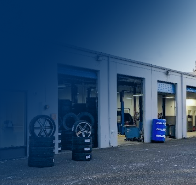 A stack of tires sits outside of a garage | TIRE NATION & AUTO REPAIR POINT S