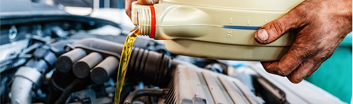 A person is pouring oil into a car engine. | TIRE NATION & AUTO REPAIR POINT S