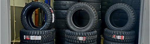 A bunch of tires are stacked on top of each other in a garage. | TIRE NATION & AUTO REPAIR POINT S