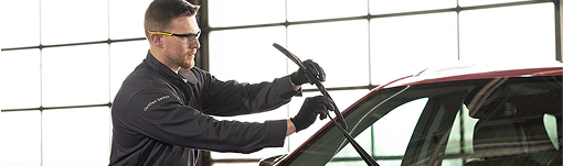 A man is cleaning the windshield of a car in a garage. | TIRE NATION & AUTO REPAIR POINT S