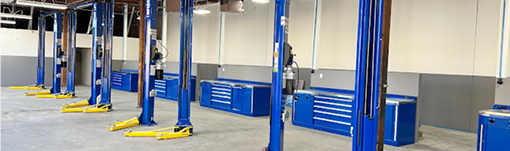 A row of blue and yellow lifts in a garage. | TIRE NATION & AUTO REPAIR POINT S