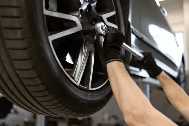 A man is changing a tire on a car with a wrench. | TIRE NATION & AUTO REPAIR POINT S