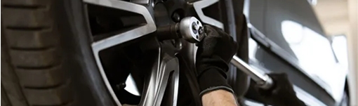 A person is working on a car wheel with a wrench. | TIRE NATION & AUTO REPAIR POINT S