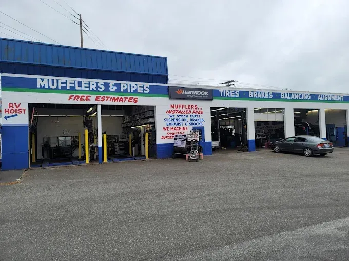 A car is parked in front of a shop that sells mufflers and pipes | TIRE NATION & AUTO REPAIR POINT S