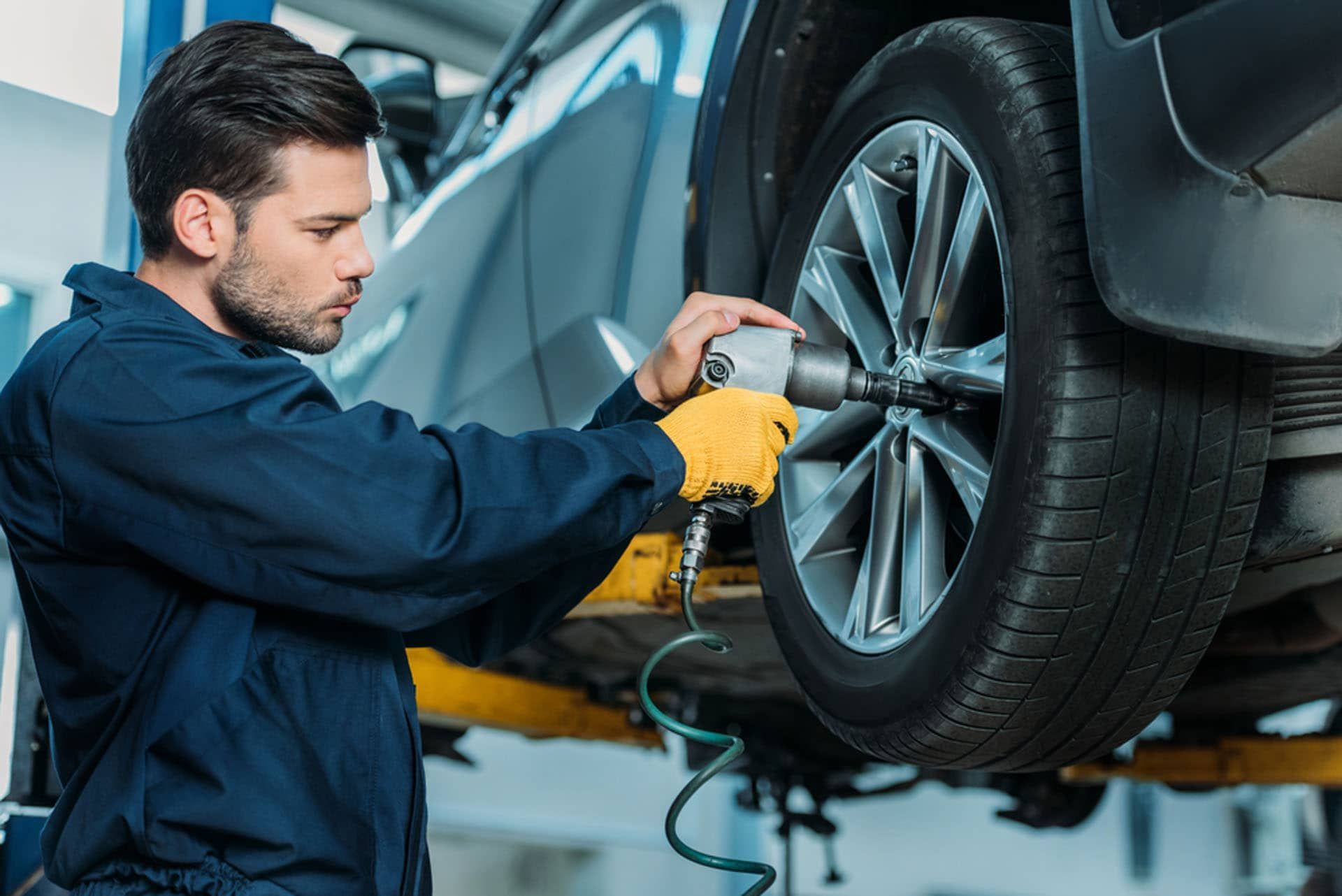 A man is changing a tire on a car in a garage. | TIRE NATION & AUTO REPAIR POINT S