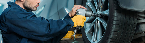 A man is working on a car wheel with a wrench. | TIRE NATION & AUTO REPAIR POINT S