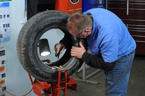 A man is working on a tire in a garage. | TIRE NATION & AUTO REPAIR POINT S