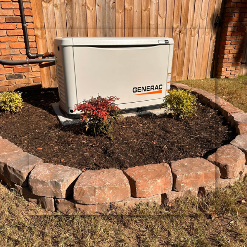 A white Generac home generator on a concrete base, set against a brick wall.