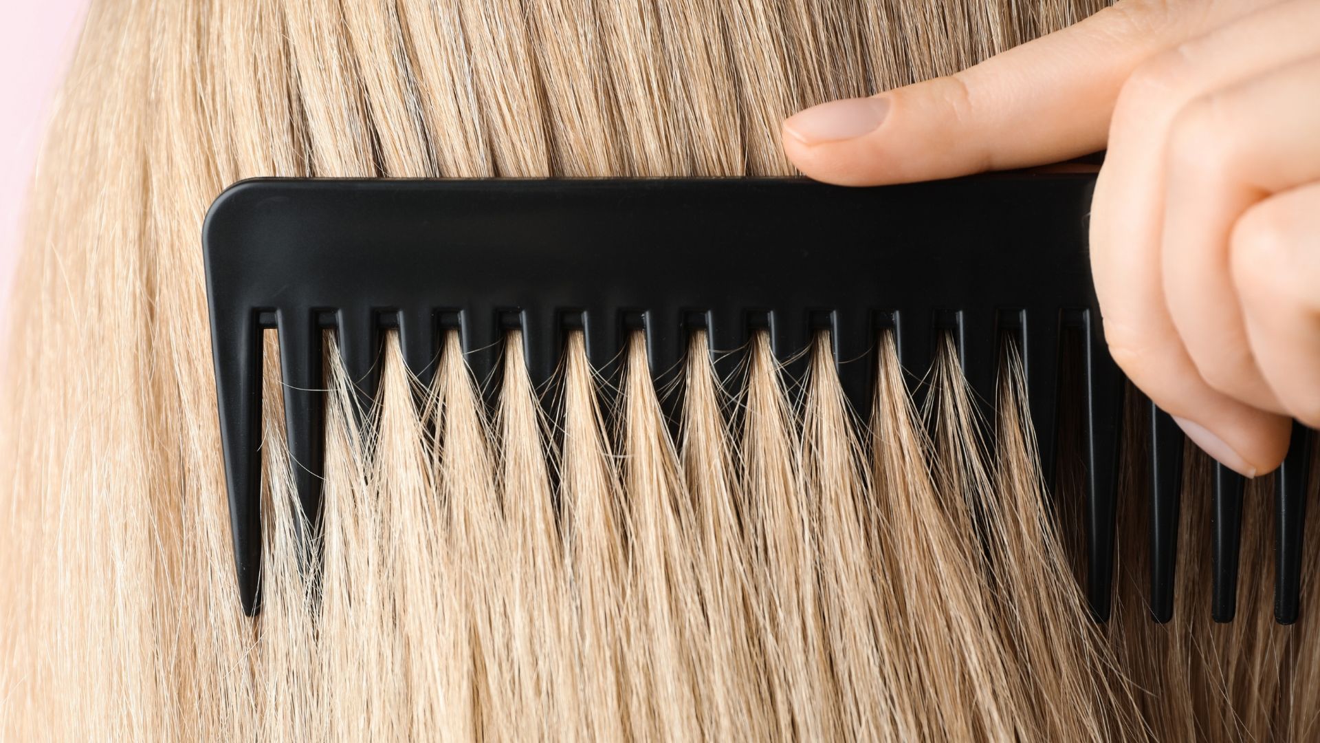Hand combing light blonde hair with a black comb.