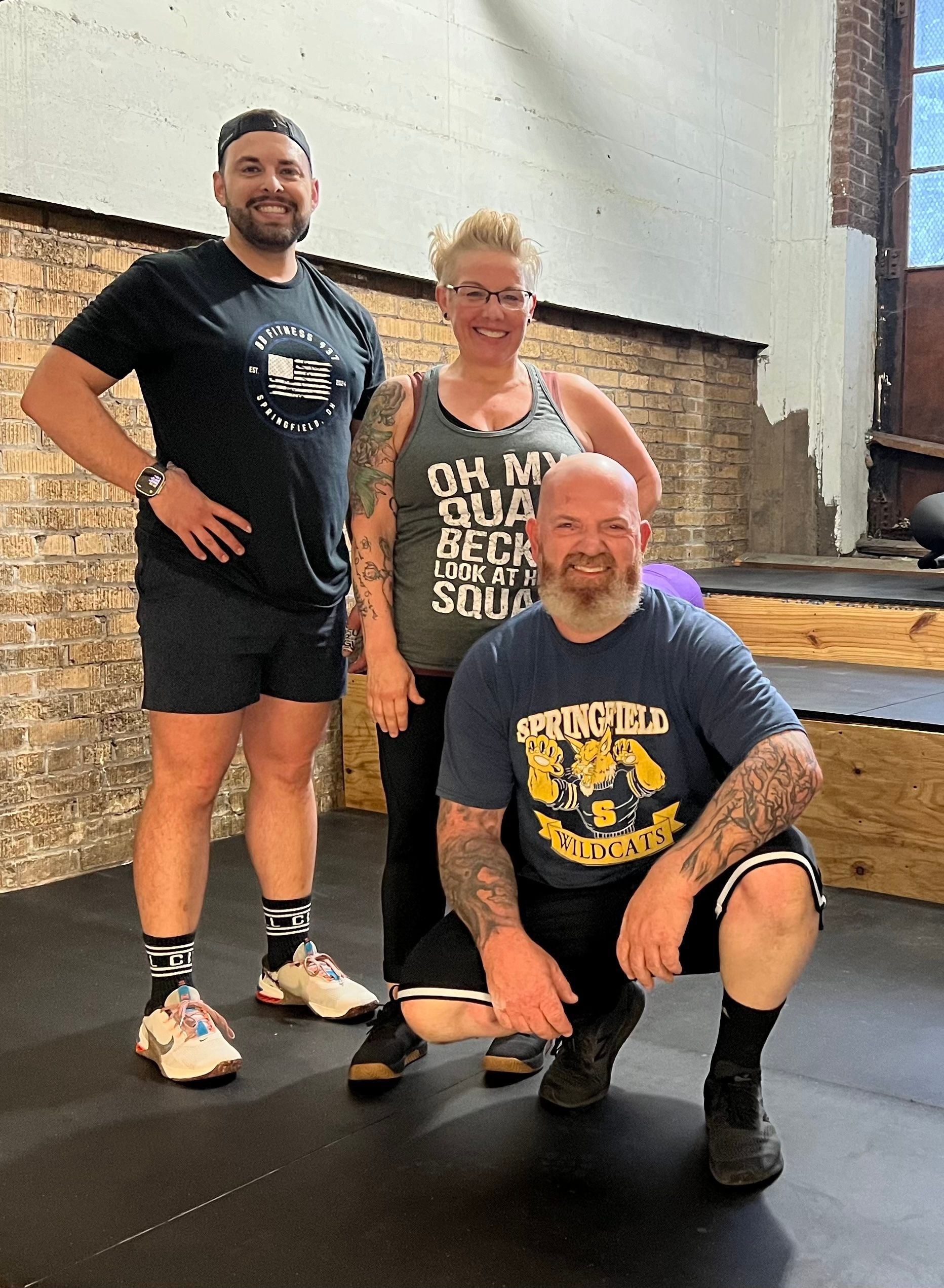 Three people are posing for a picture in a gym.