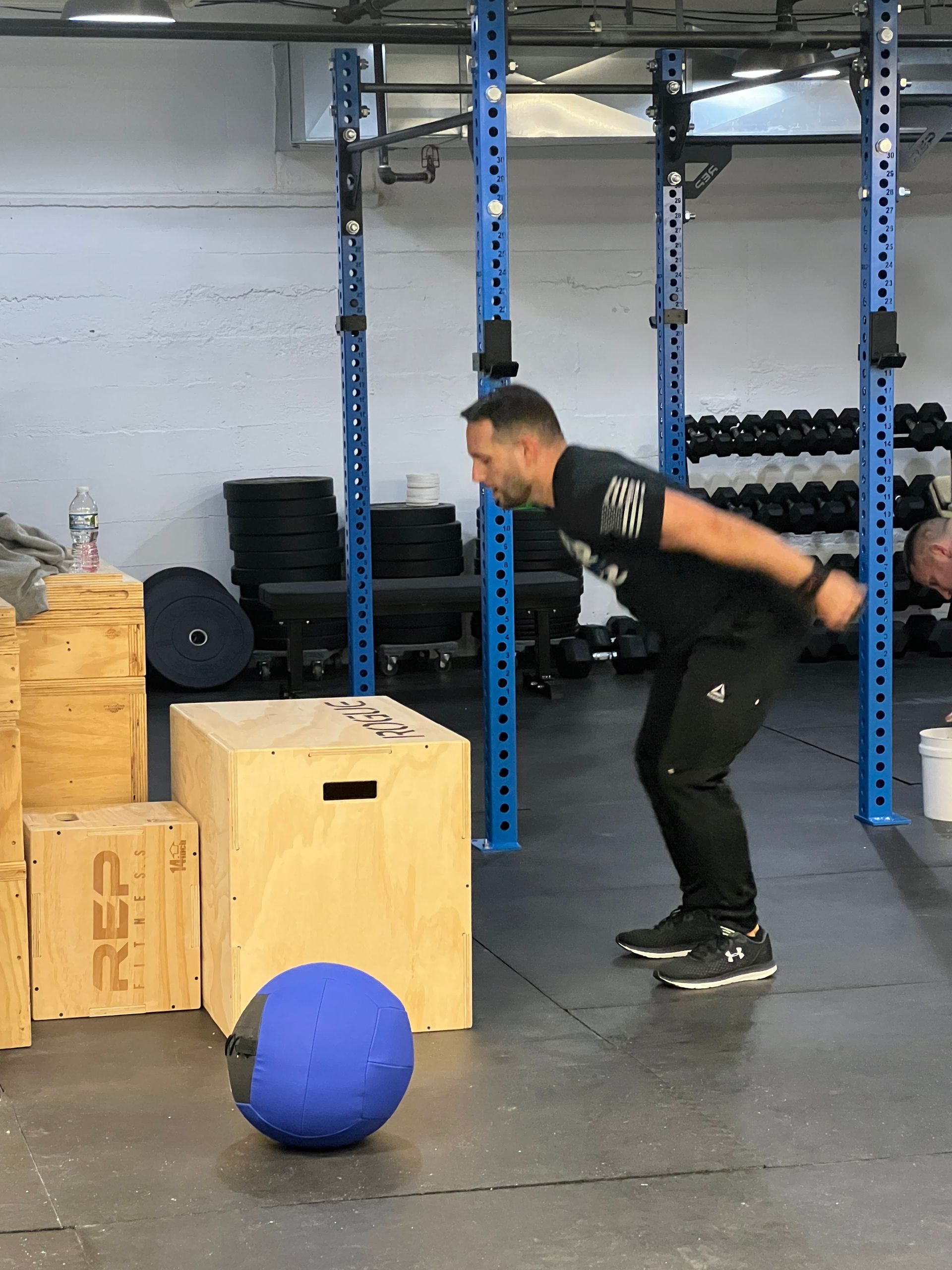 A man is doing exercises with a blue ball in a gym