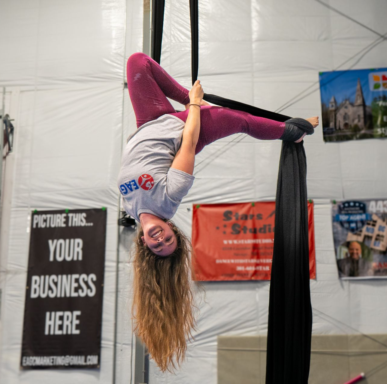 aerial silk coach hanging upside down from the silk in a special pose