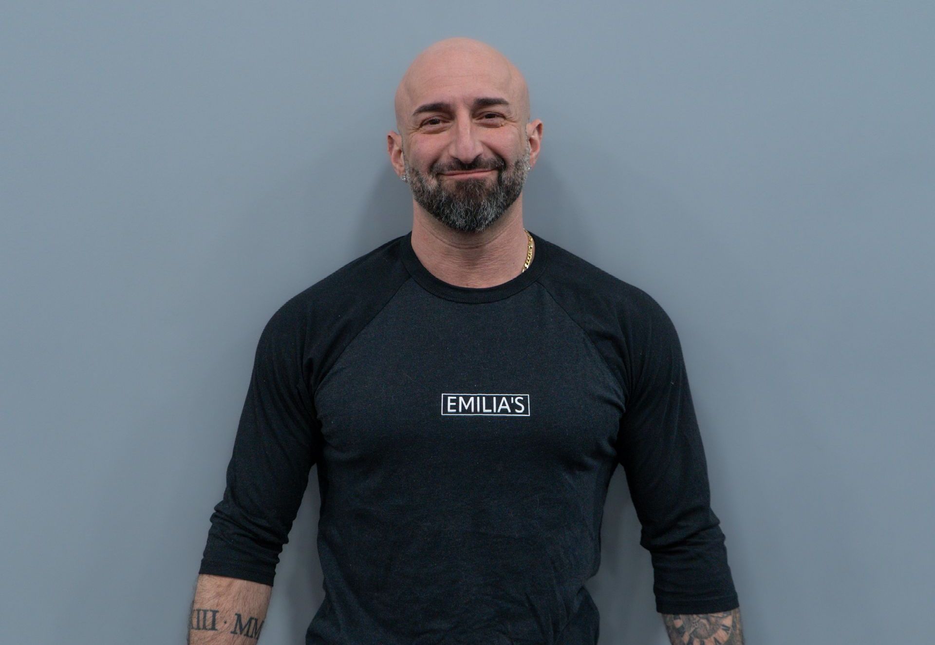 A bald man with a beard is wearing a black shirt with the word dallas on it.