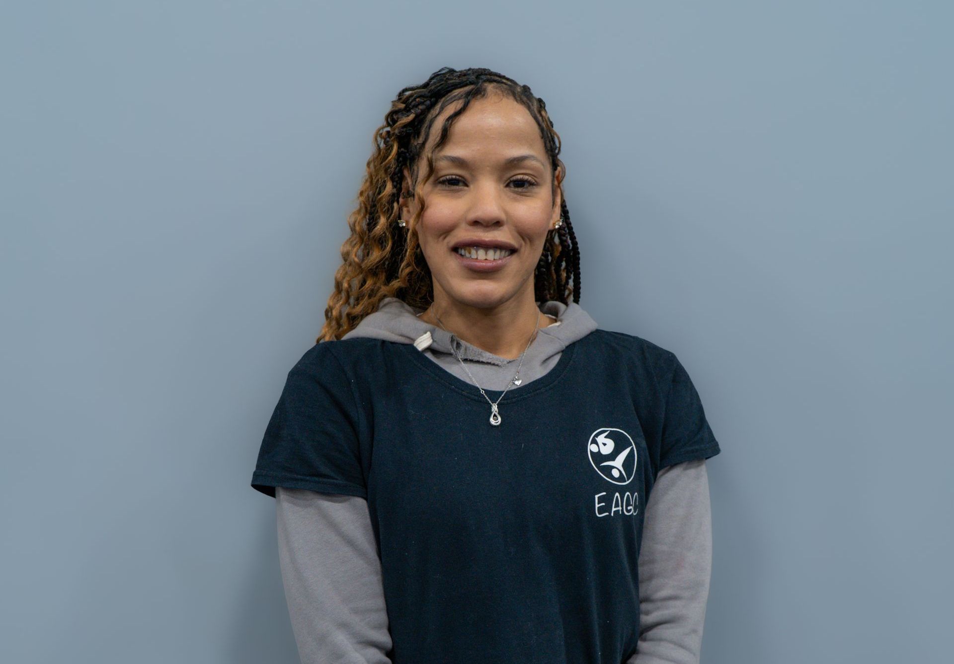 A woman wearing glasses and a gray shirt is smiling for the camera.