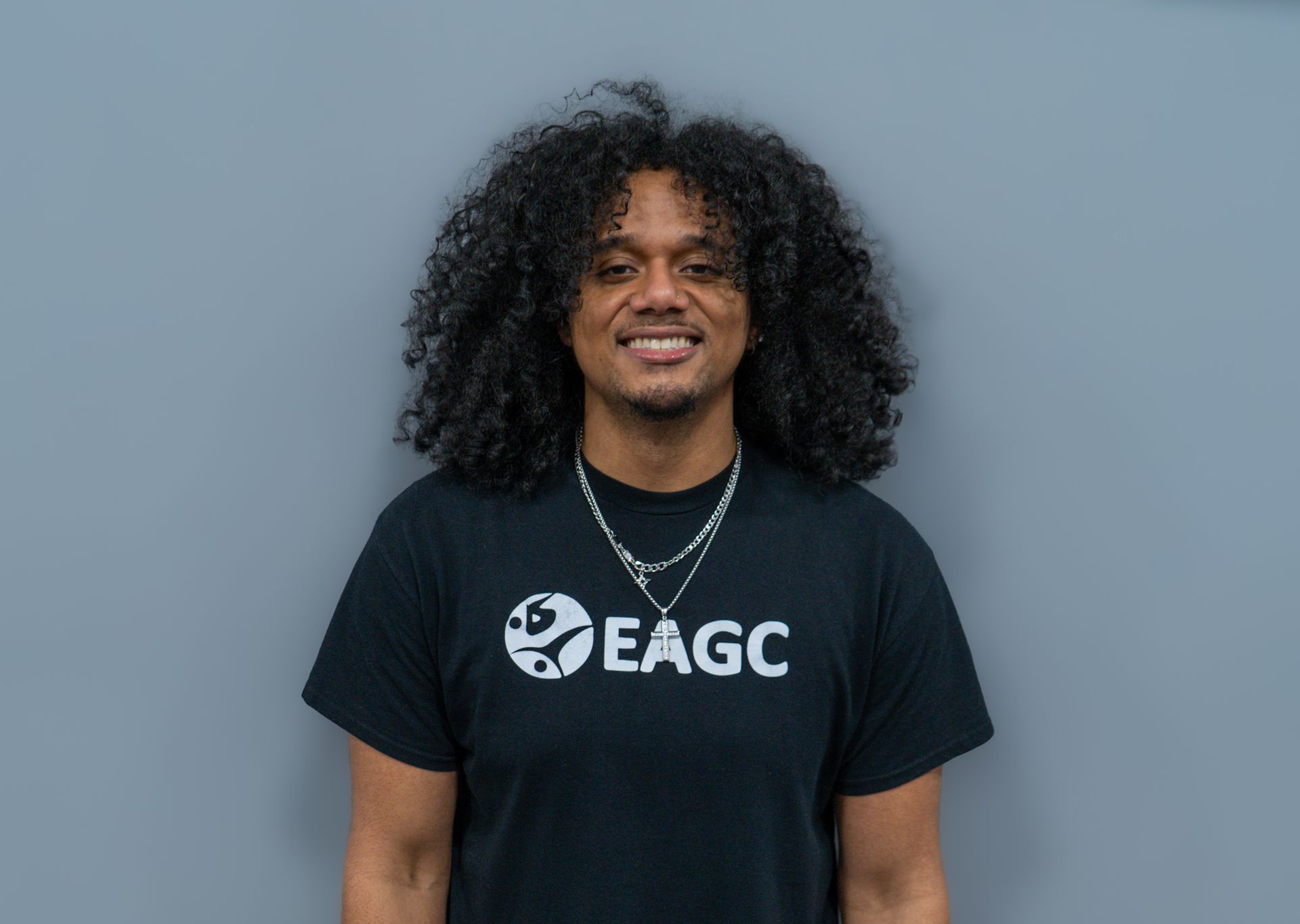 A man with curly hair is holding a volleyball in his hand.