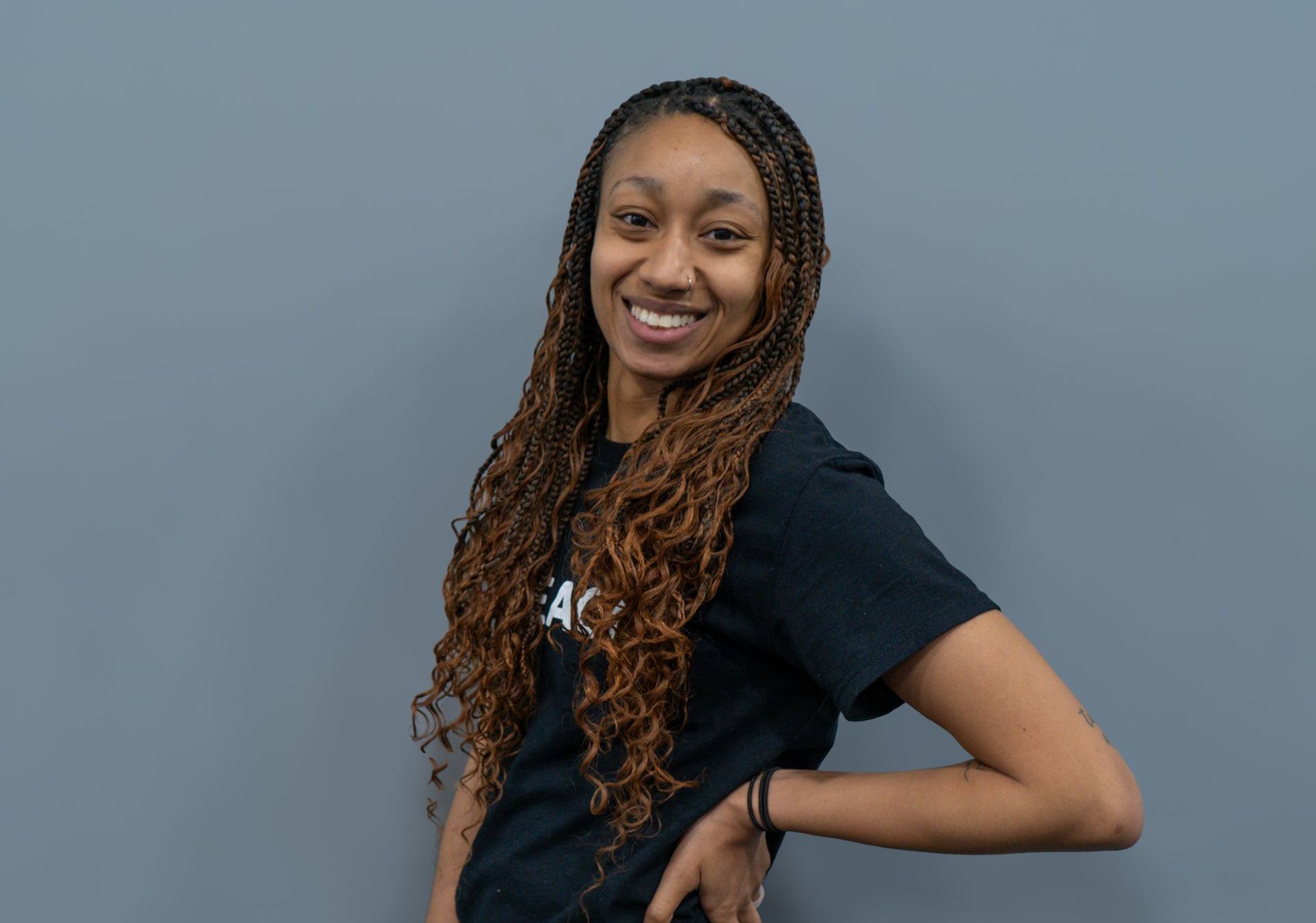 A young woman wearing a grey t-shirt and red shorts is standing with her hands on her hips.