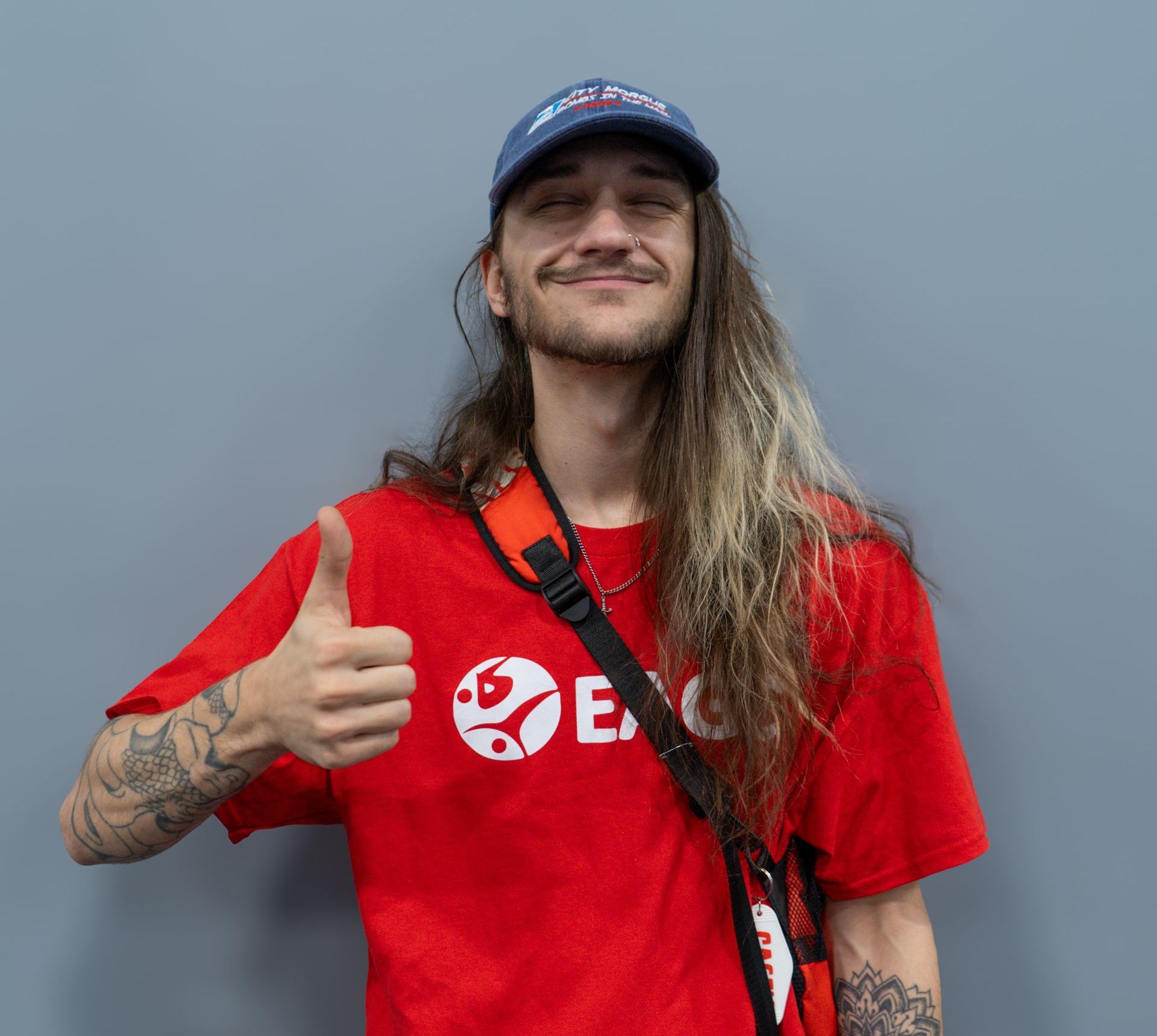 A man wearing glasses and a white t-shirt giving a peace sign
