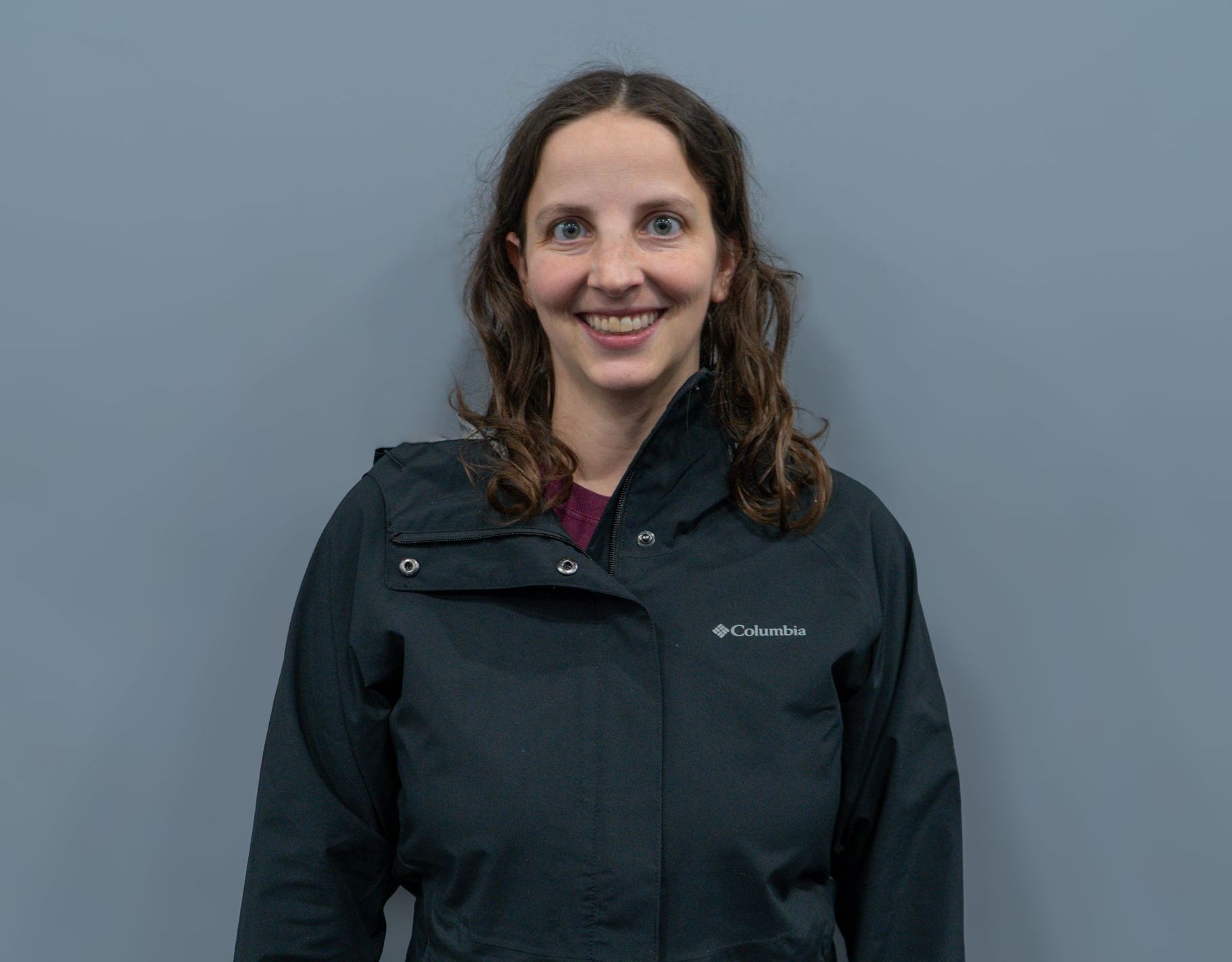 A woman in a black jacket is smiling for the camera.