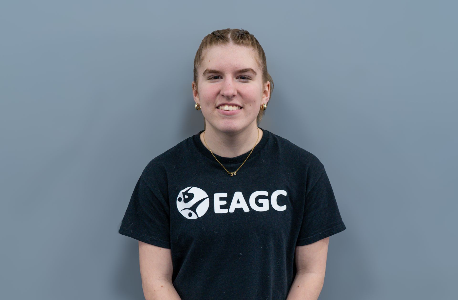 A woman in a black EAGC t-shirt is smiling for the camera.