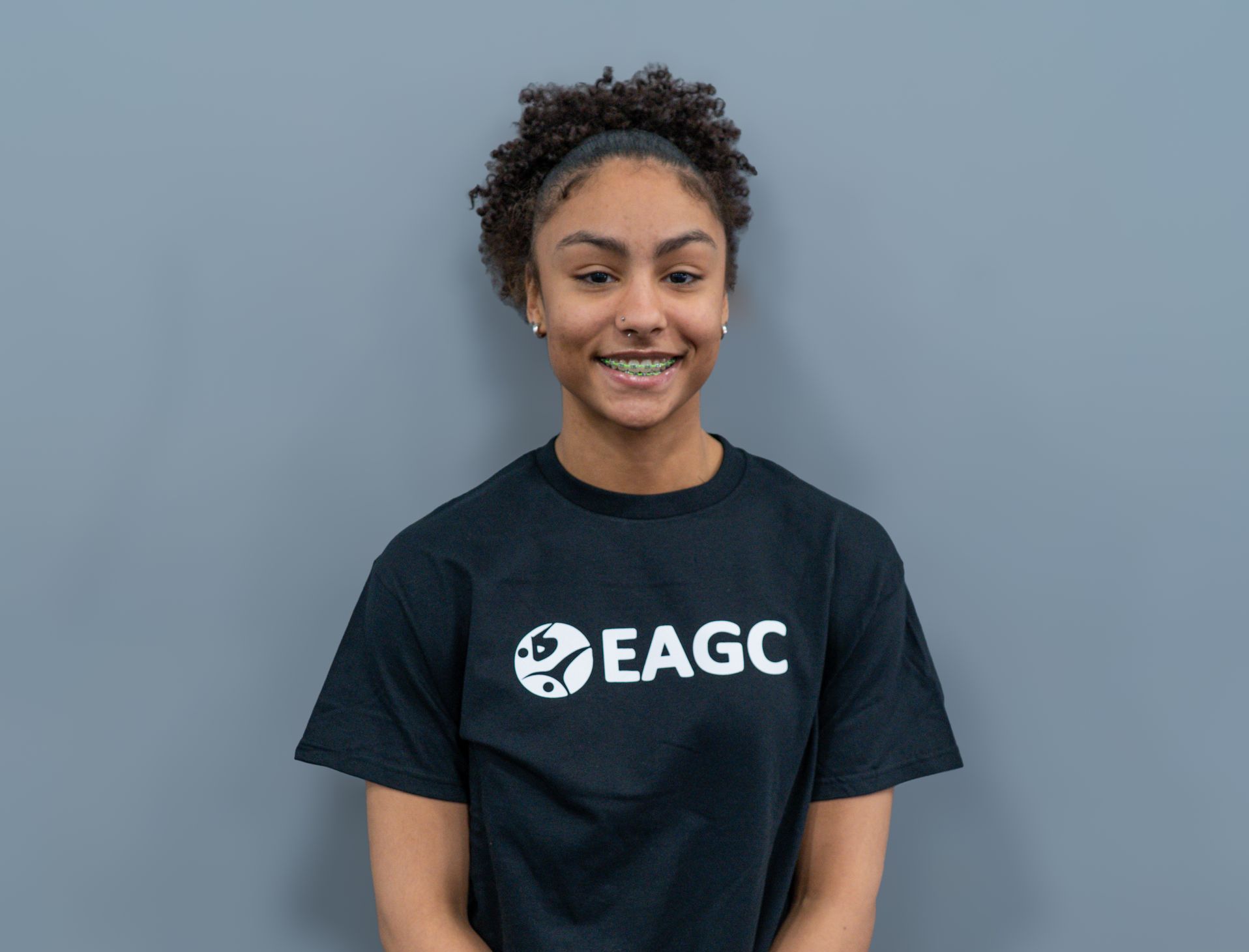 A smiling woman in a black EAGC t-shirt.