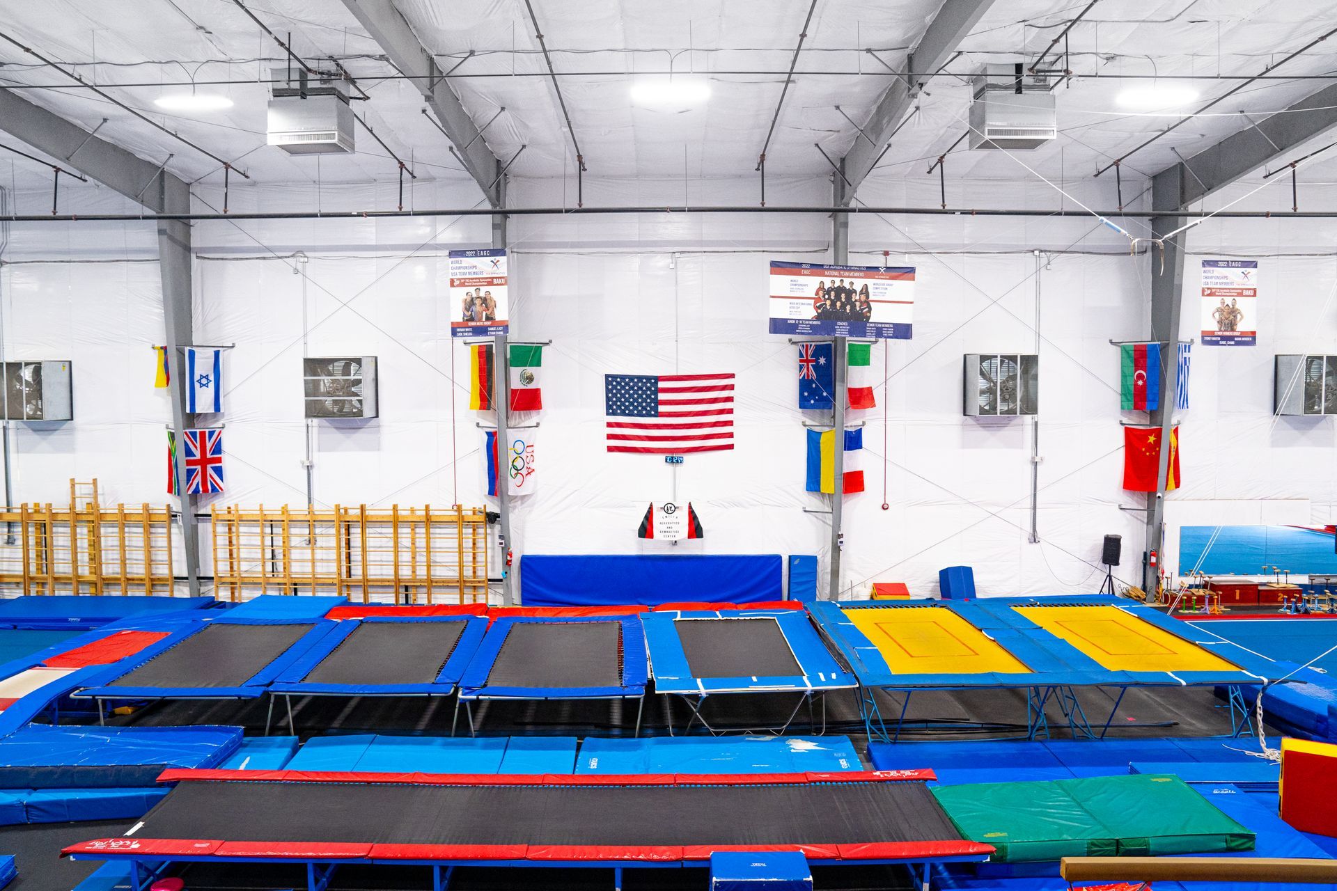 A gym with a lot of trampolines and flags on the wall.