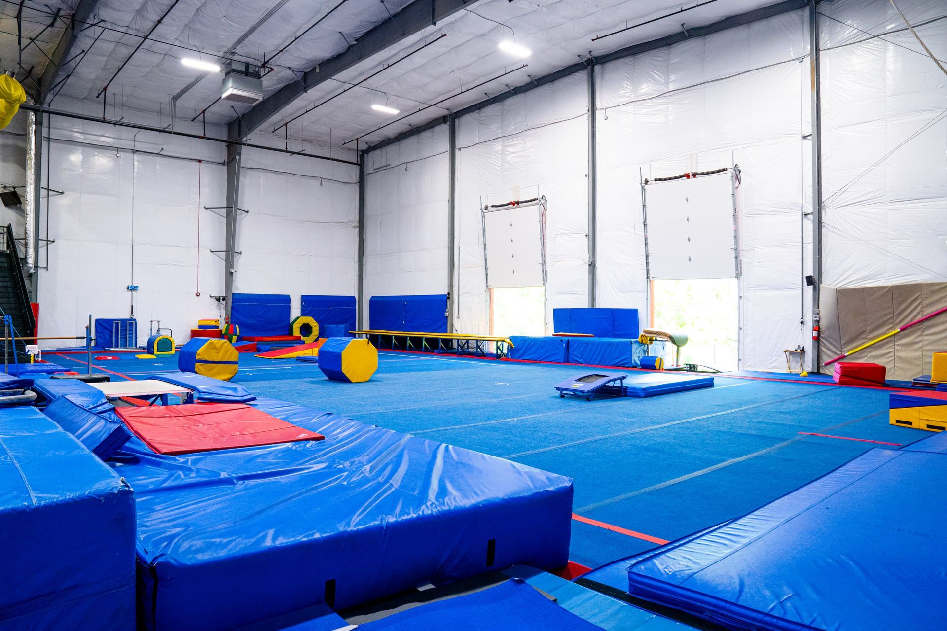 A large gym filled with blue mats and a bunch of equipment.