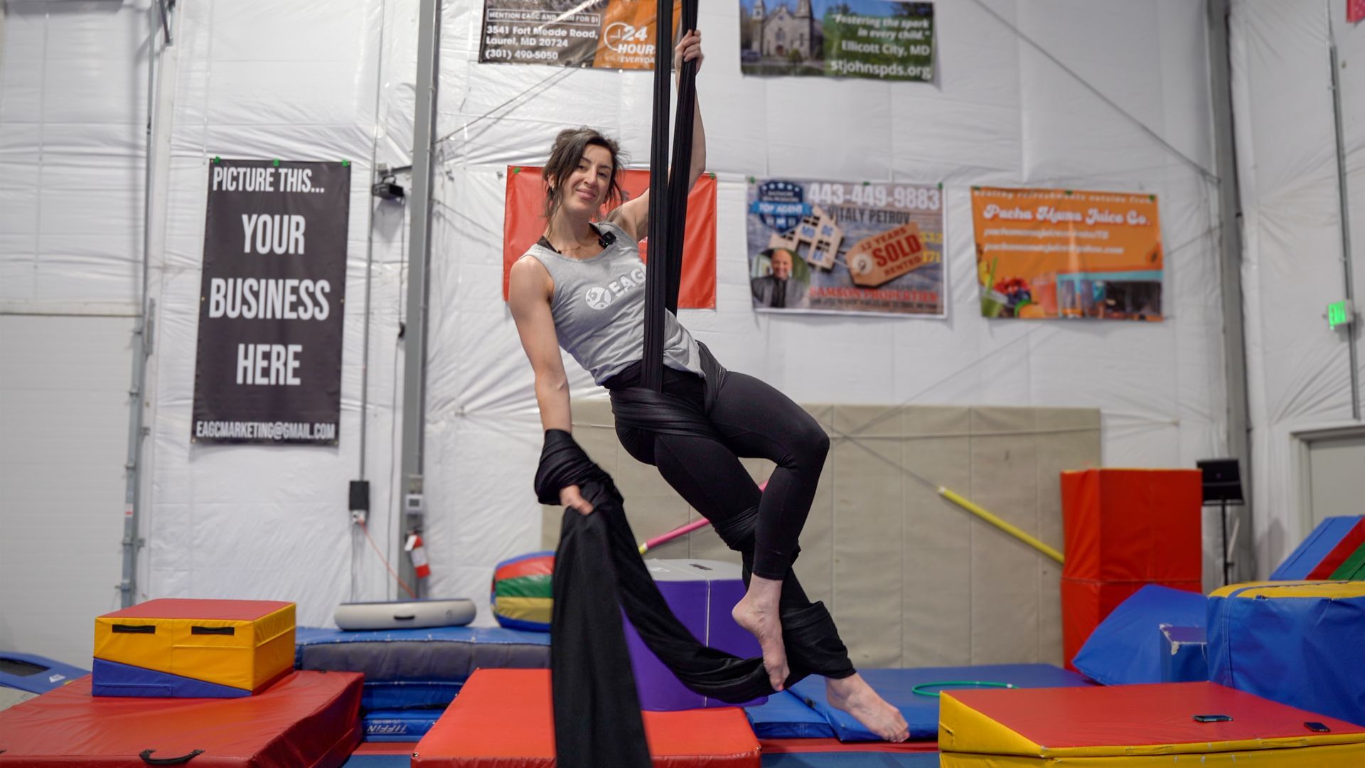 our aerial silk coach Amanda showing off a pose while hanging on the silks