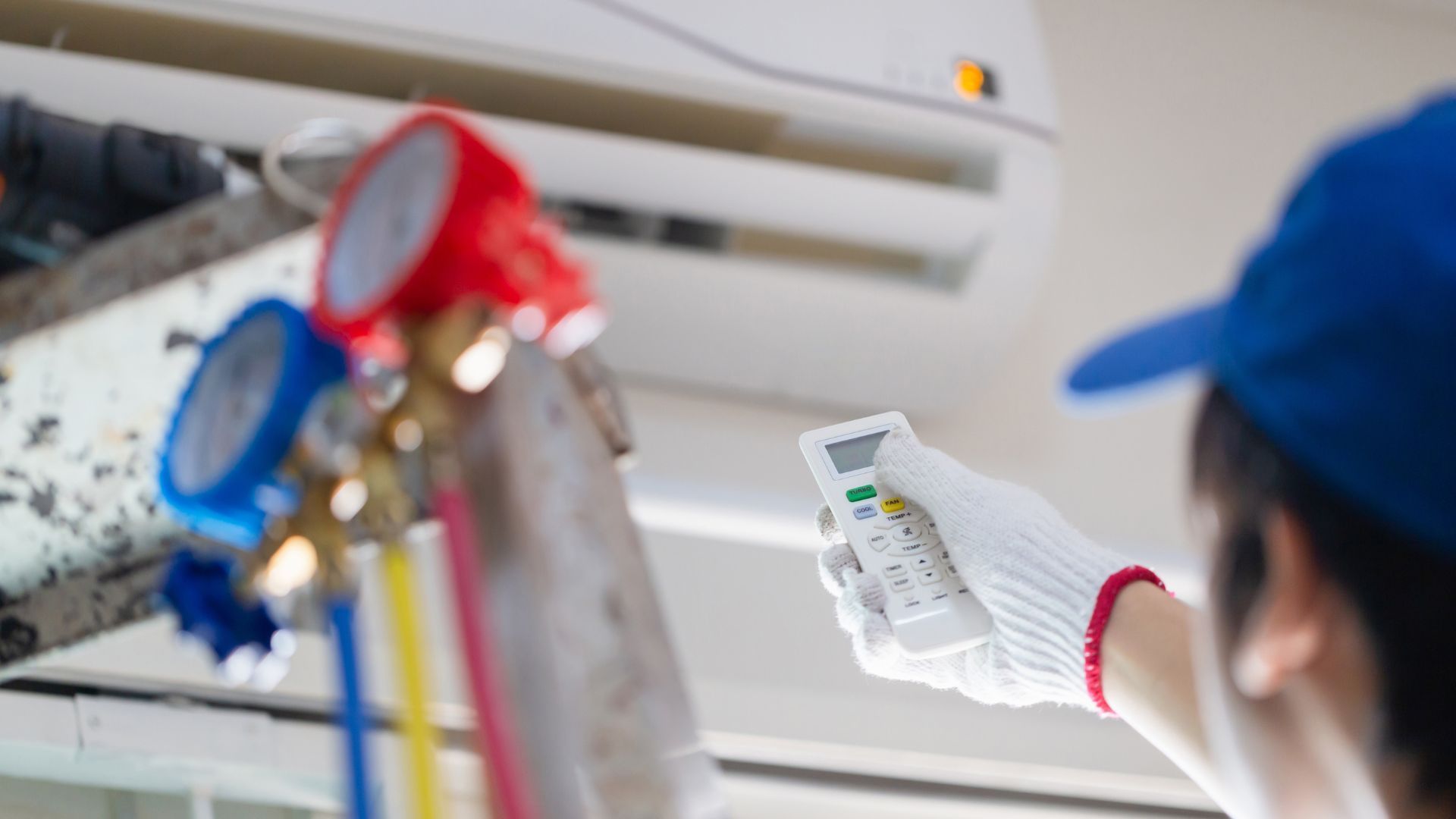 A man is holding a remote control while working on an air conditioner.