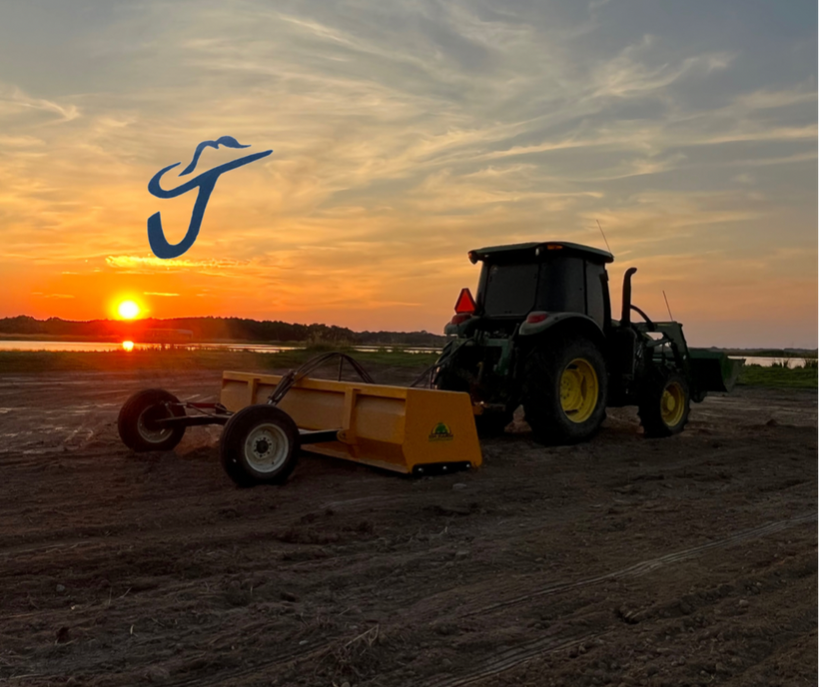 Green tractor on field at the sunset