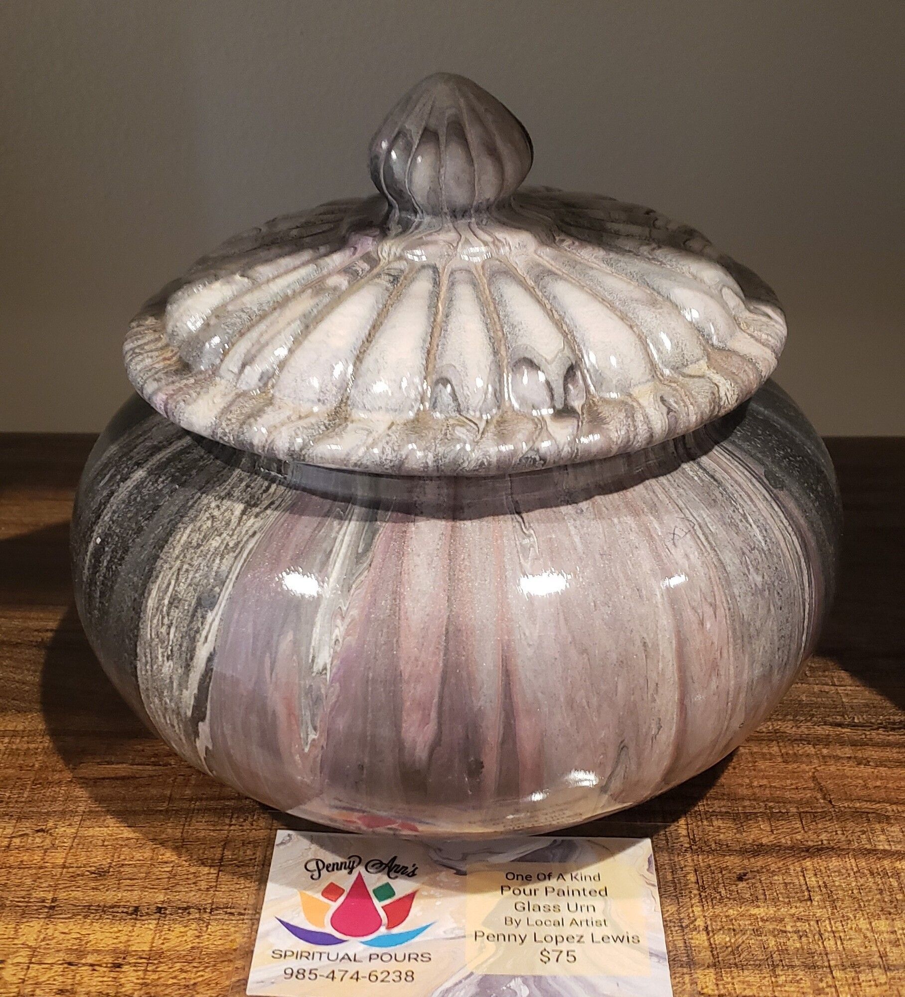 A marbled gray and white ceramic jar with a lid, on a wooden surface.