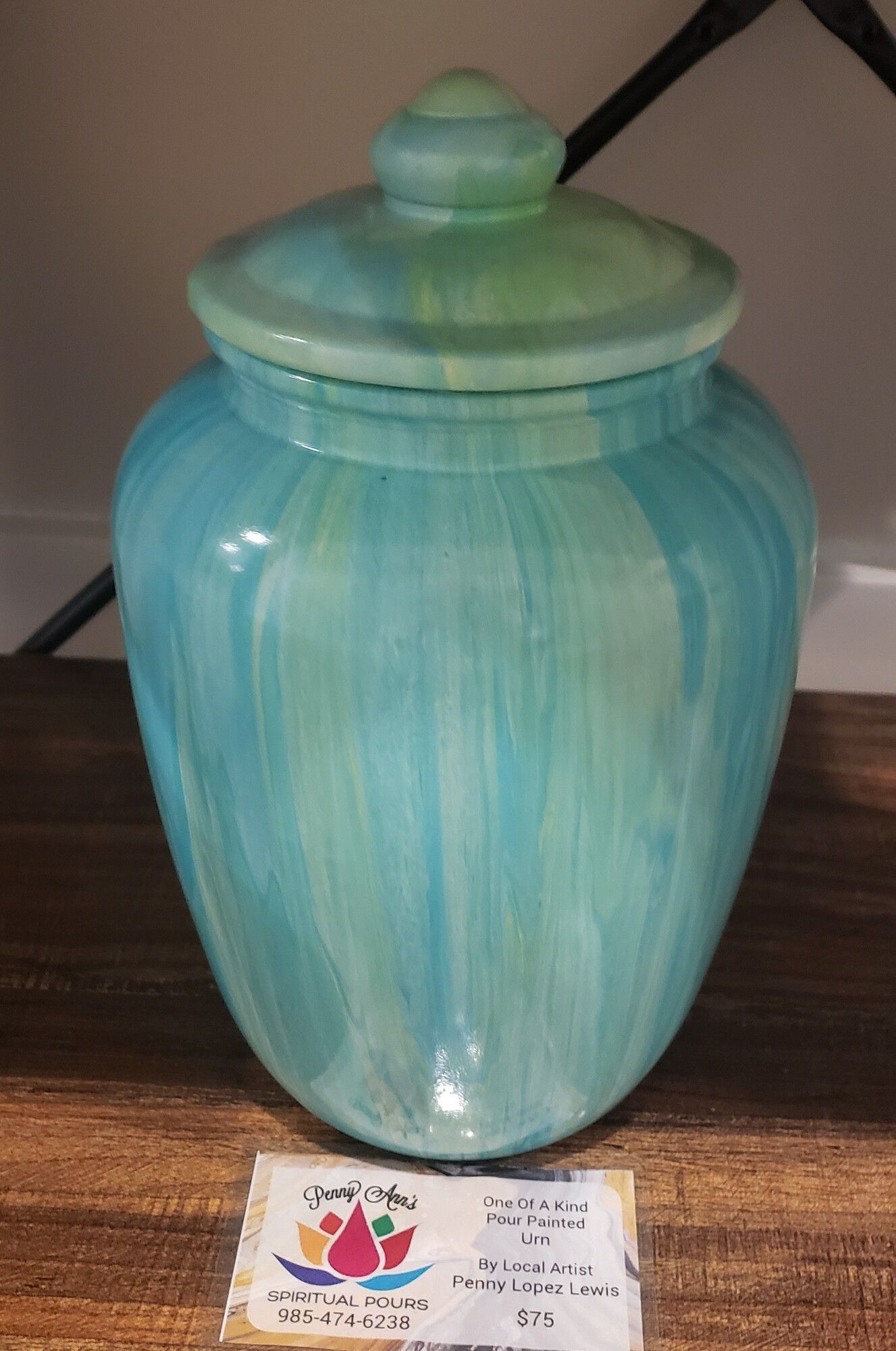 Blue and green ceramic urn with lid on a wooden surface.
