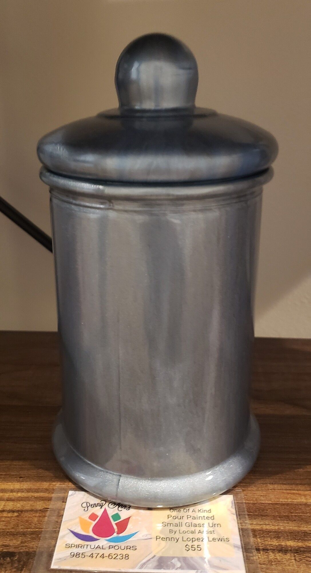 Gray metal canister with lid on a wooden shelf.