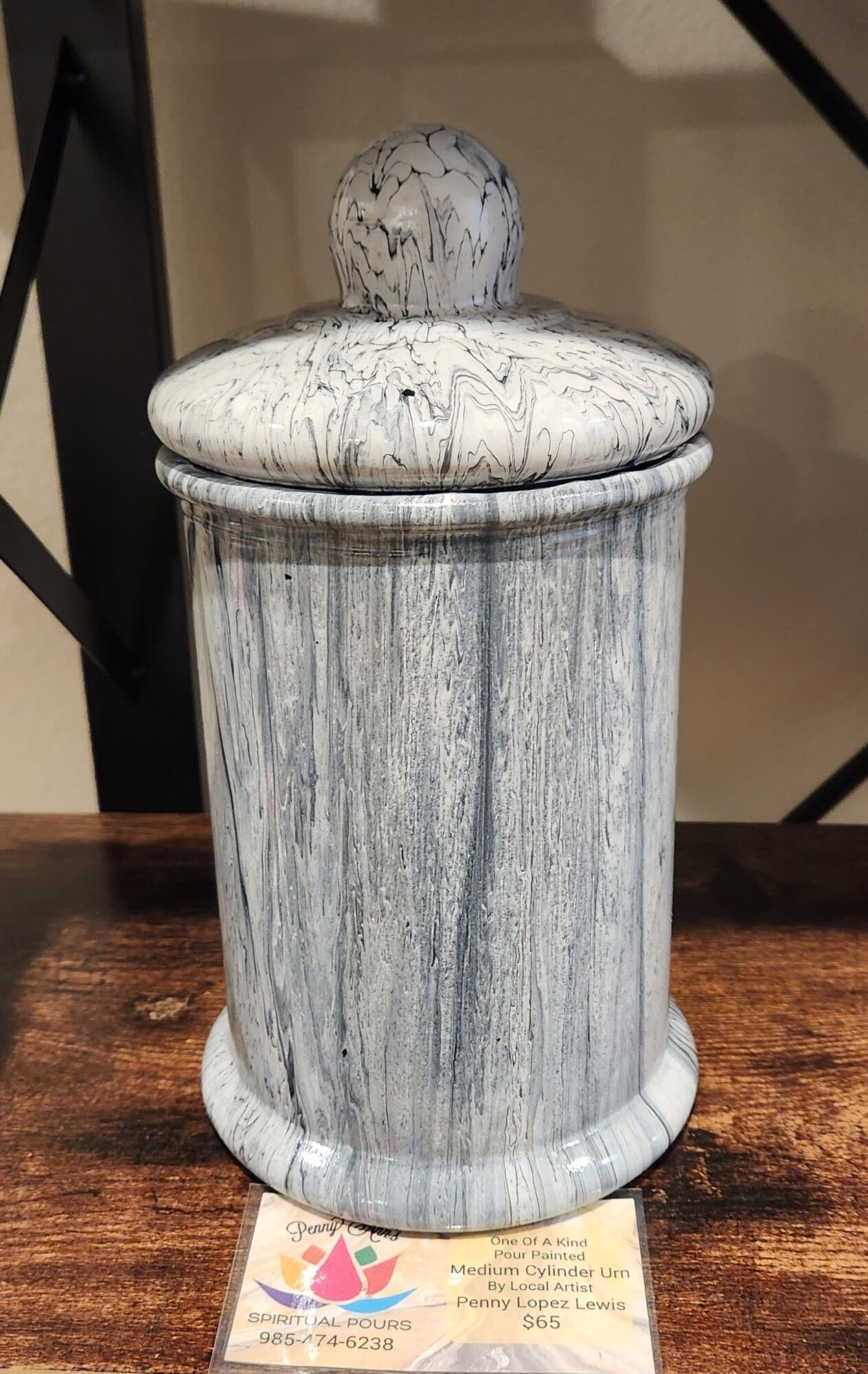 A speckled ceramic jar with a lid on a wooden surface.