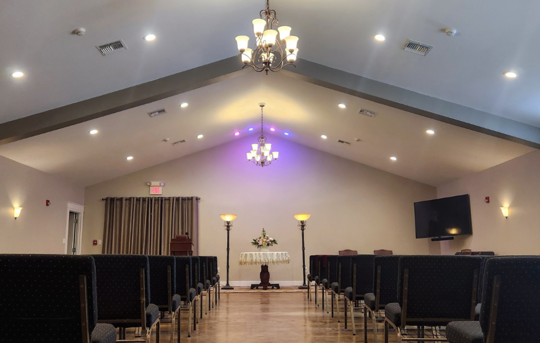 Interior of Hughes funeral home chapel with chairs, altar, and chandeliers.