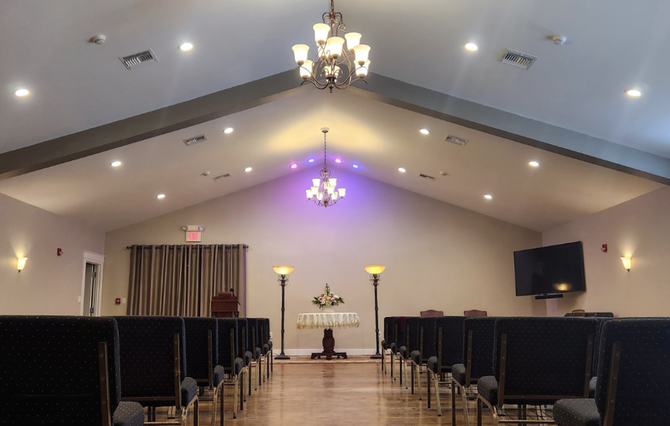Interior of Hughes funeral home chapel with chairs, altar, and chandeliers.