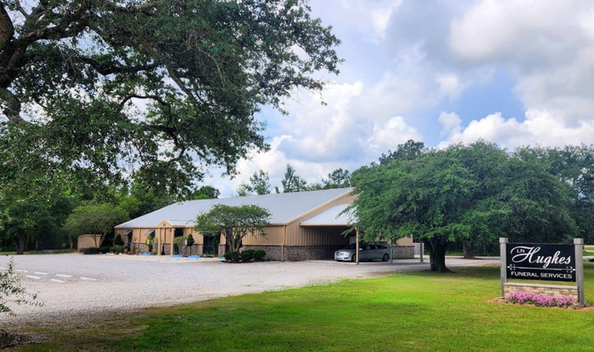 Hughes Funeral Services beige building with a metal roof, a sign that reads 