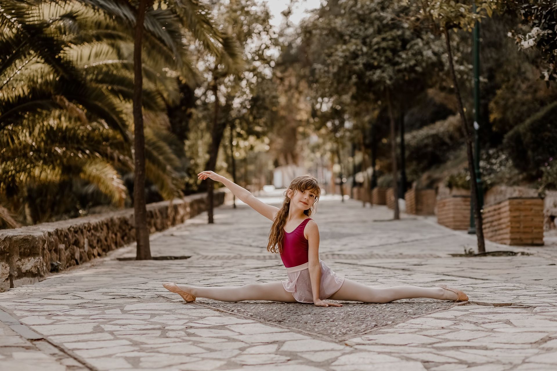 Una mujer joven está haciendo un split en el suelo en un parque.