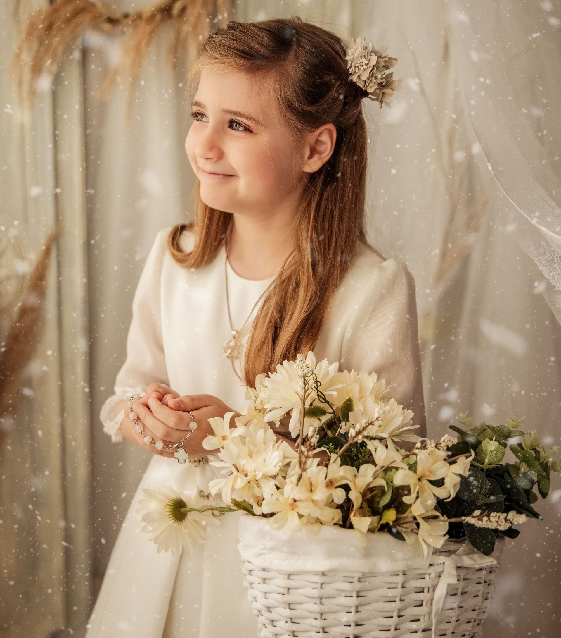una niña con un vestido blanco sostiene una canasta de flores.