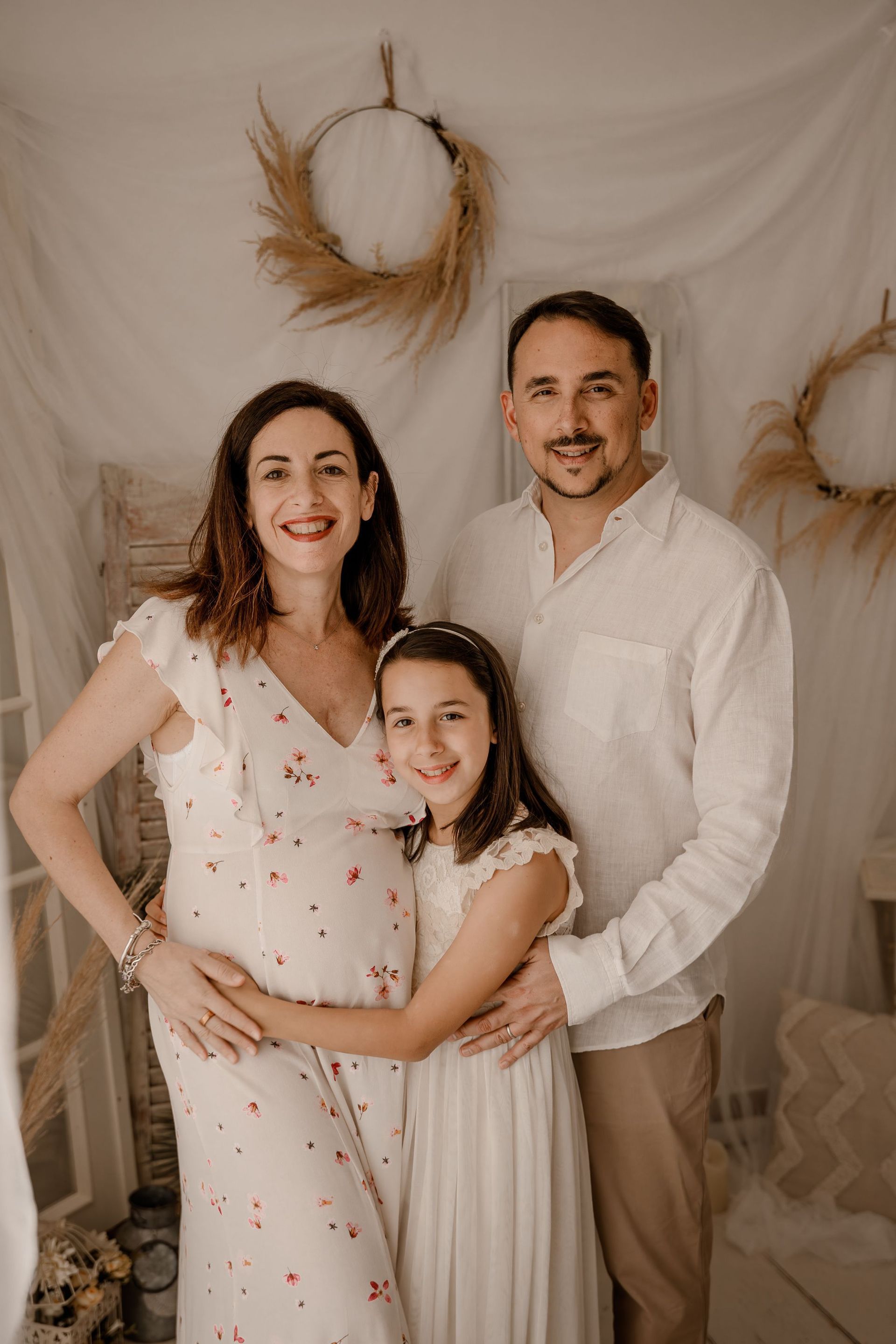 Una mujer embarazada posa para una fotografía con su marido y su hija.