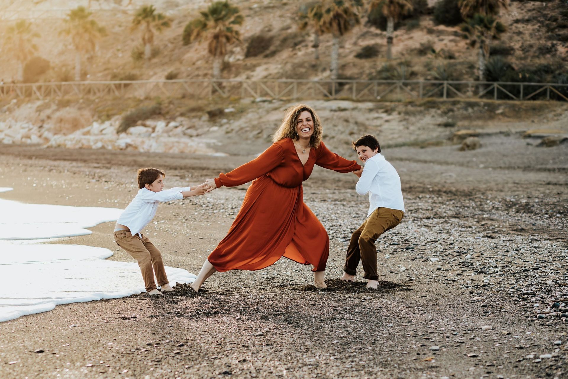 Una mujer y dos niños están jugando en la playa.