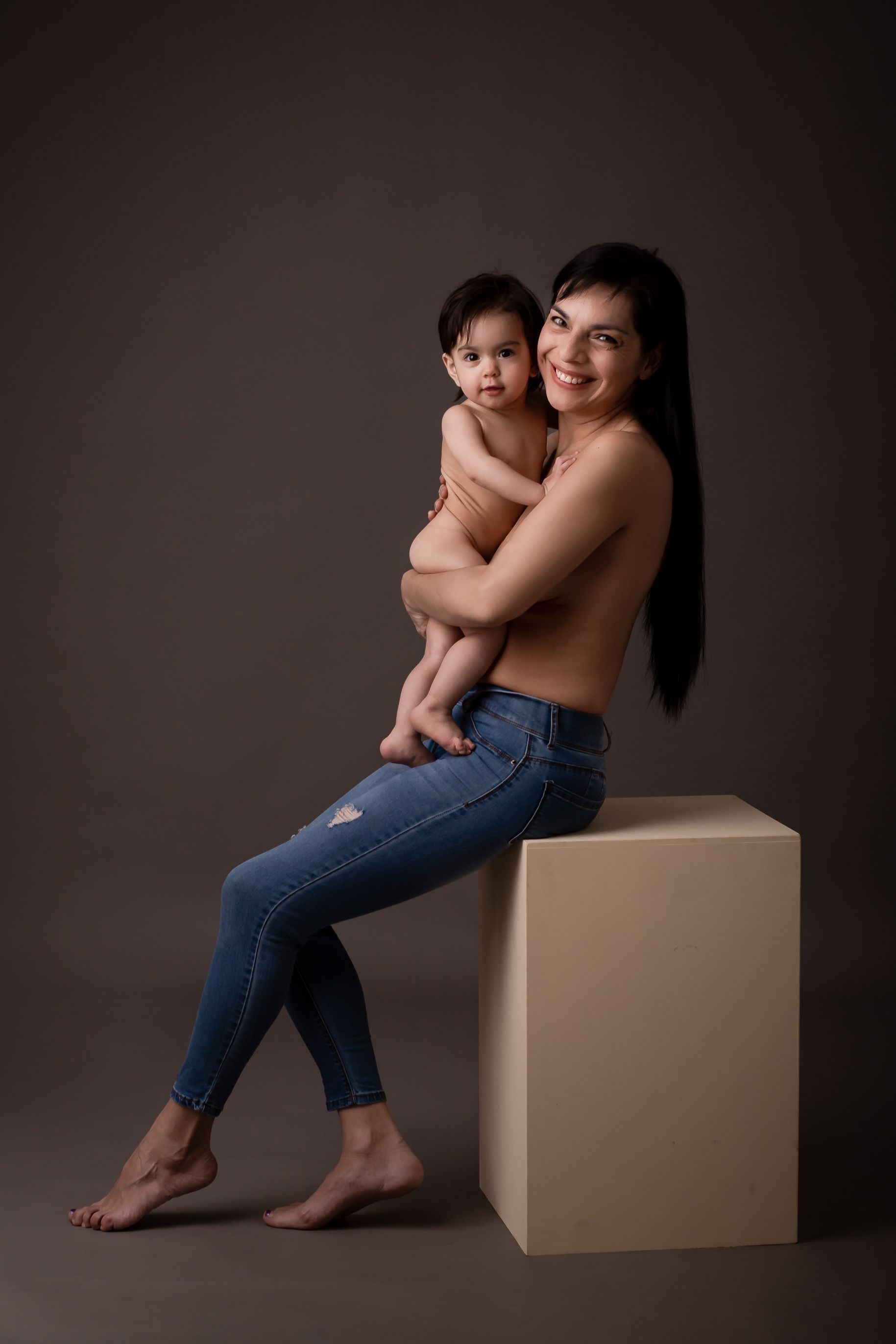Una mujer está sentada en un cubo sosteniendo un bebé.